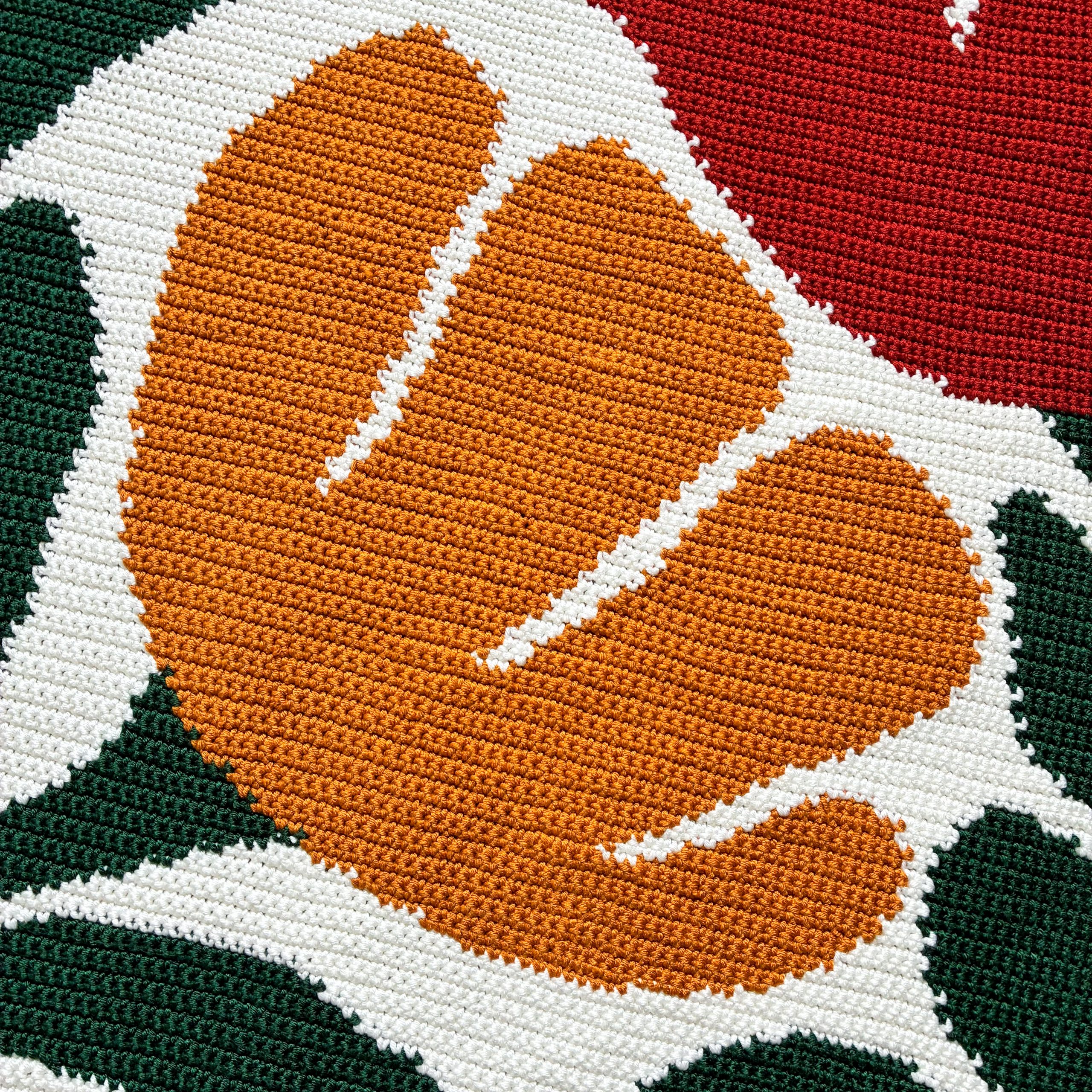 Bloom By Bloom Blanket Yellow Flower Detailed close-up of an orange-yellow flower motif in the Bloom By Bloom crochet graphgan blanket, showing textured single crochet stitches, cream outlines, and dark green leaves.